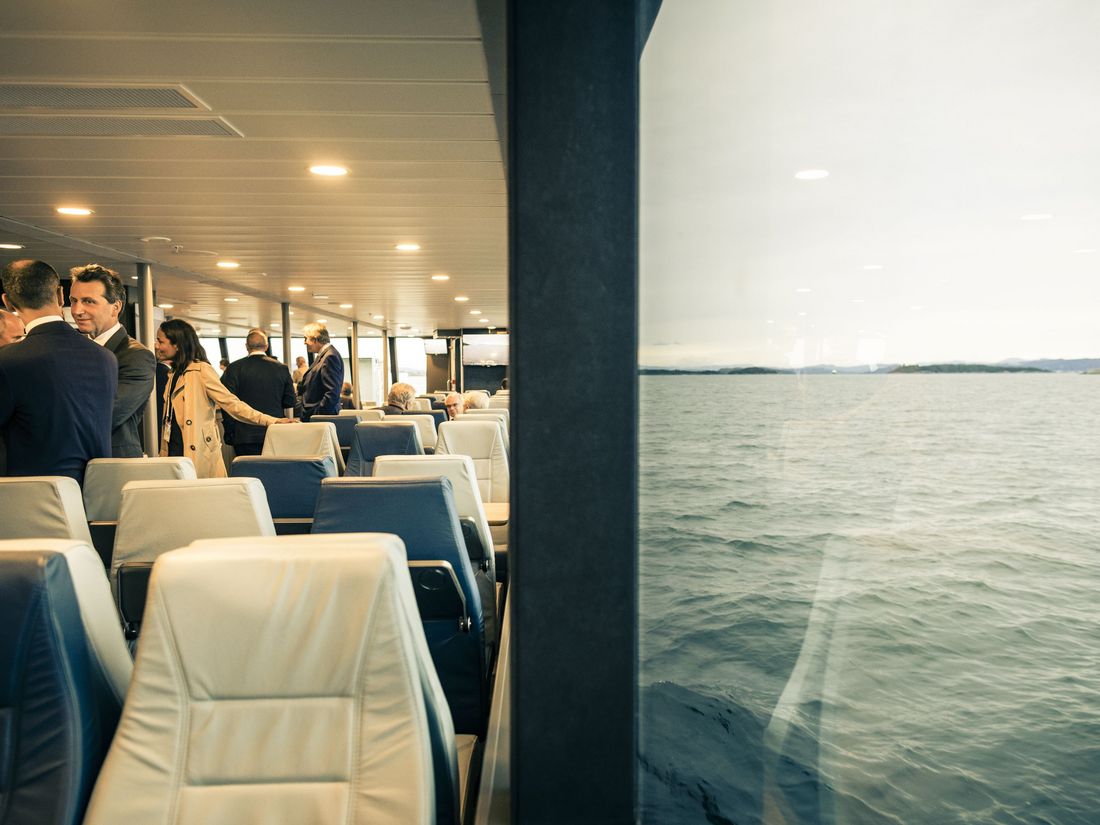 Menschen unterhalten sich in einer Fähre mit einem Blick auf das Meer durch große Fenster